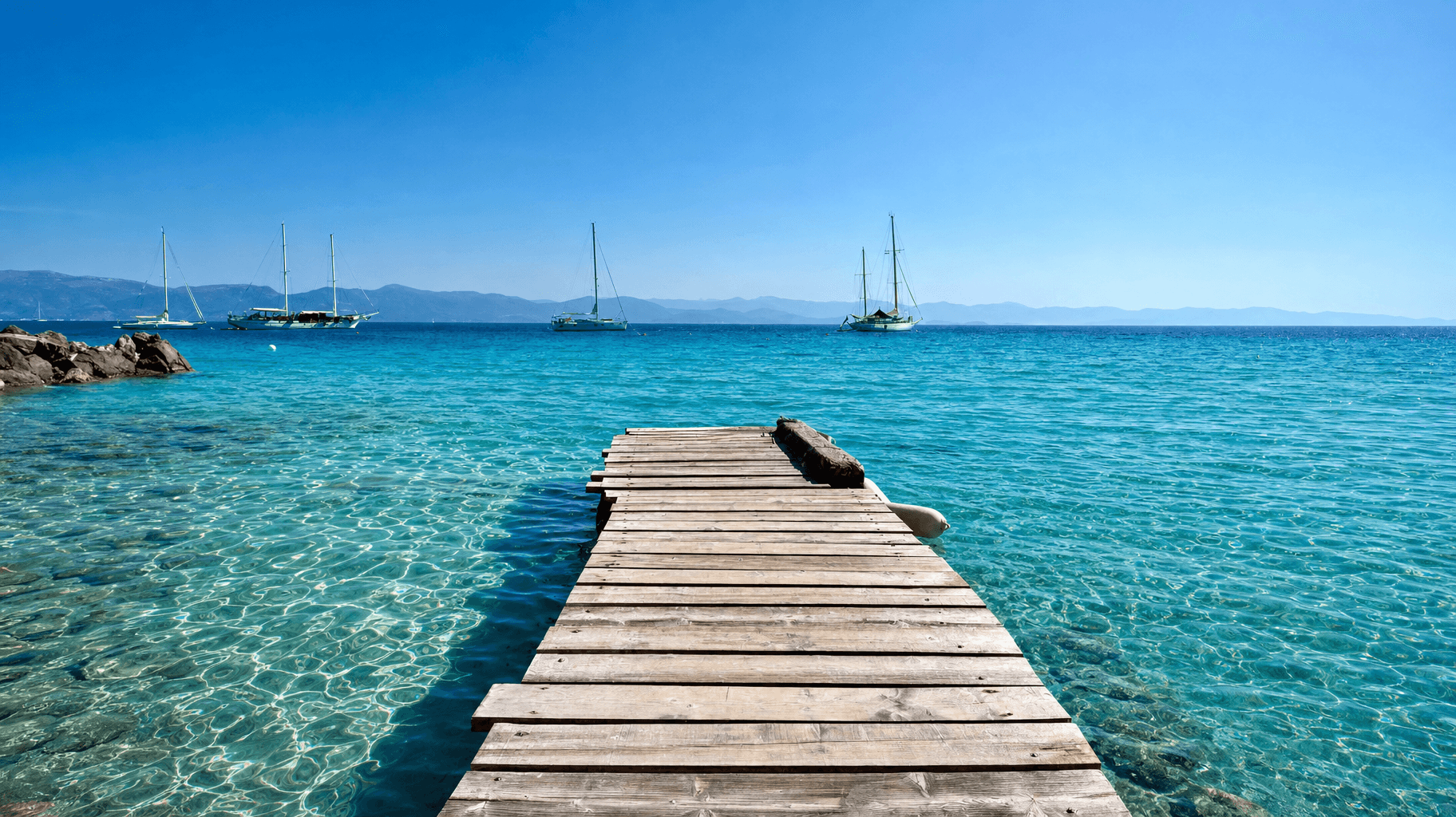 paxos-wooden-jetty-anchored-sailboats